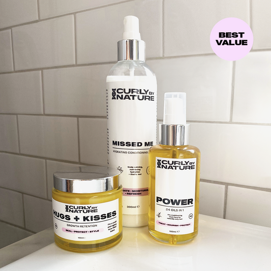 Three hair care products from Curly by Nature, including a spray bottle labeled 'MISSED ME', a conditioner bottle labeled 'POWER', and a small container labeled 'HUGS & KISSES'.